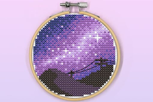 A silhouetted mountain with a milky way made of purples, scattered with stars in the night sky.