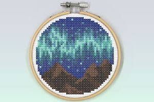 A band of northern lights in mint and light blue colours seen above some mountains.